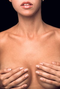 Portrait of young woman covering breasts with hands